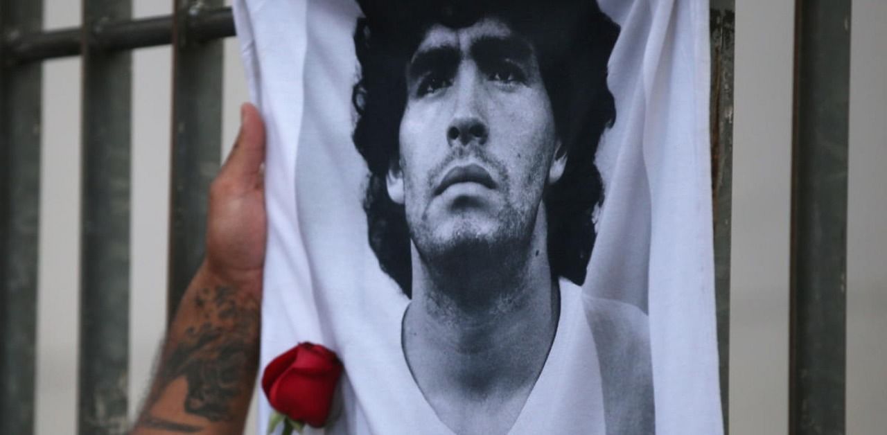 A rose is placed next to a banner of Argentine soccer great Diego Maradona as fans gather to mourn his death at the Obelisk of Buenos Aires, Argentina. Credit: Reuters Photo