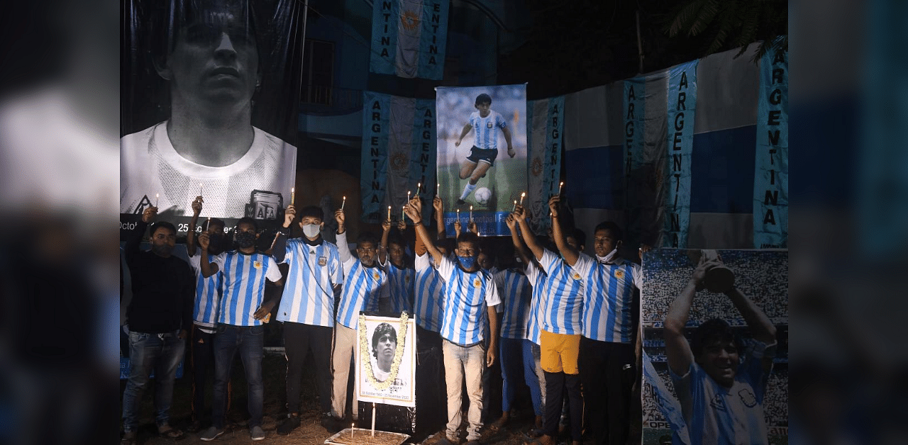 Fans hold candles as they pay homage to late Argentinian football legend Diego Armando Maradona in Kolkata on November 26, 2020. Credit: AFP Photo