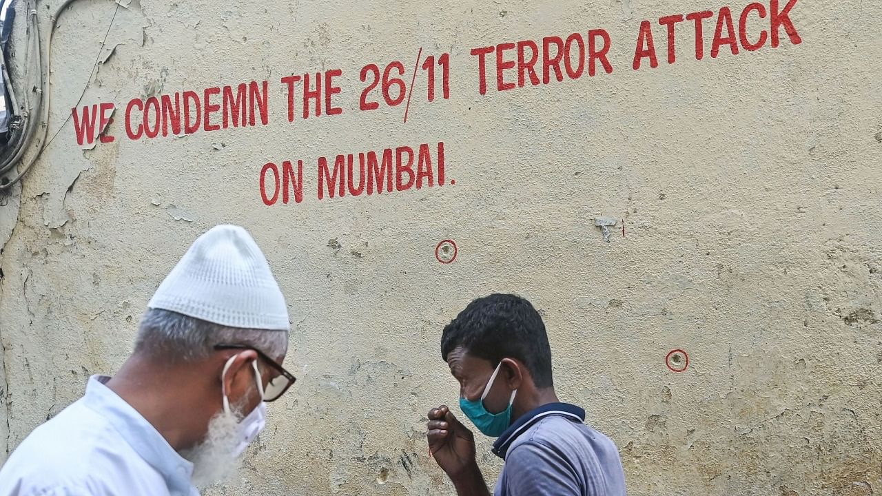 Pedestrians walk past bullet holes marked outside Nariman House, one of the sites of the 2008 Mumbai terror attacks that had claimed 166 lives, on the eve of the 26/11 terror attack's 12th anniversary. Credit: PTI Photo