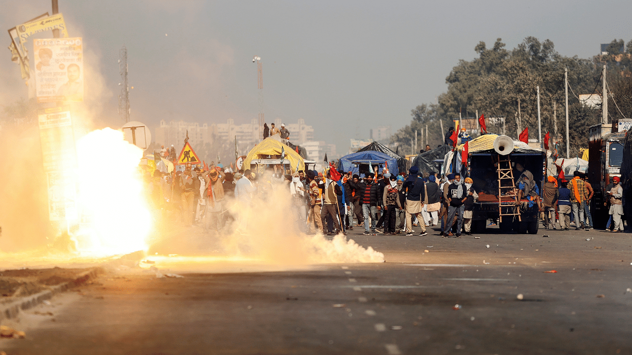 Flames emerge from tear gas released by the police to stop farmers opposing the newly passed farm bills from entering the national capital Delhi, at Singhu border, India. Credit: Reuters Photo