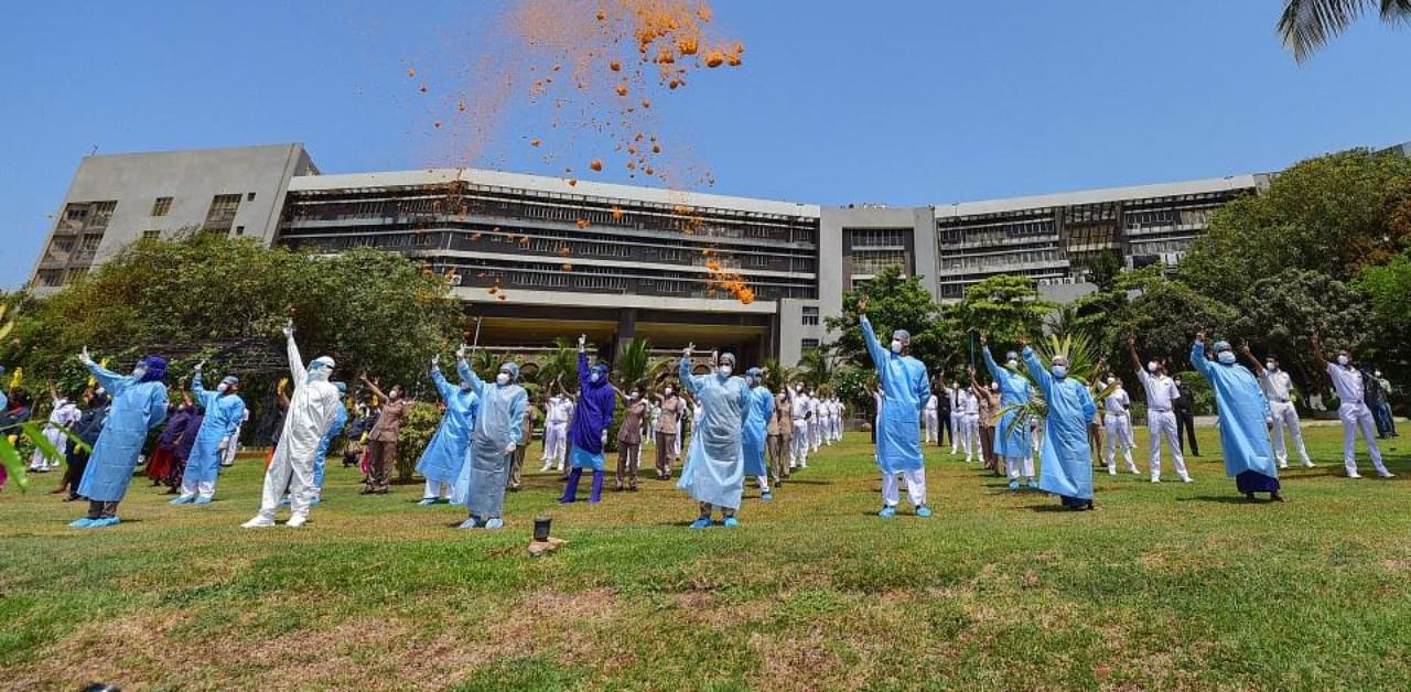 An Indian Navy helicopter showers flower petals on medics to applaud them for their services in the fight against Covid-19 at INHS Asvini. Credit: PTI Photo