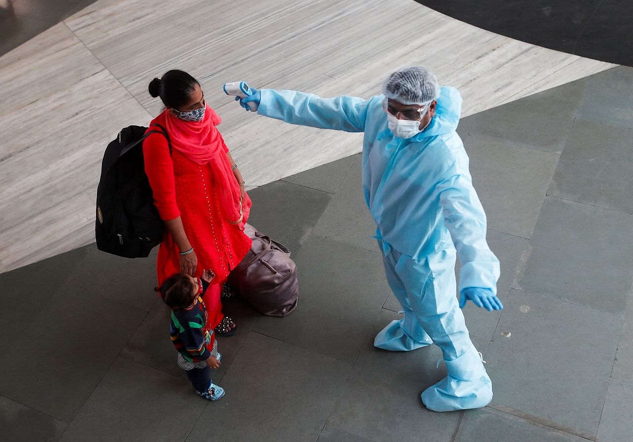 A health worker in personal protective equipment (PPE) checks the temperature of a passenger at a railway station, amid the spread of the coronavirus disease (Covid-19), in Mumbai. Credit: Reuters Photo