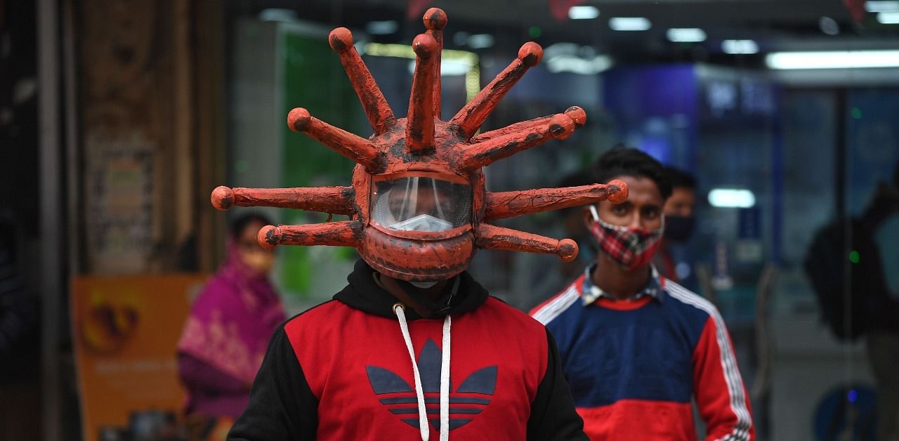 A civil defence volunteer wearing a coronavirus-themed helmet holds a placard as he takes part in an awareness campaign at a market in New Delhi. Credit: AFP Photo