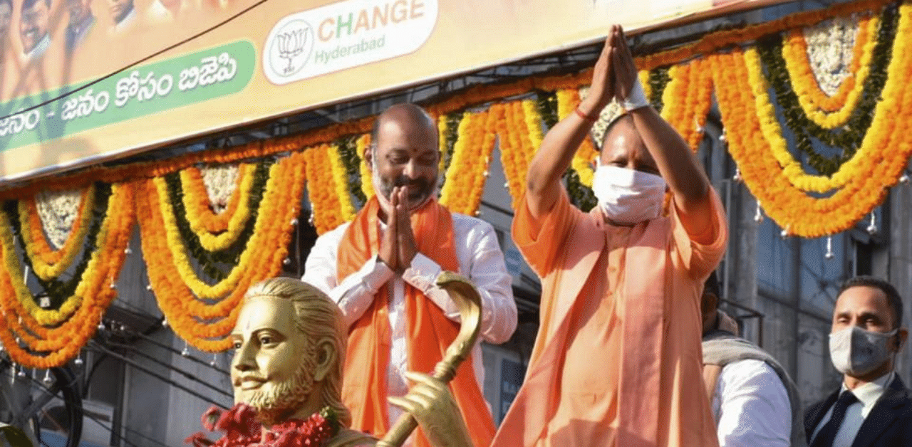 Uttar Pradesh Chief Minister Yogi Adityanath with BJP State president Bandi Sanjay waves at supporters during a roadshow, ahead of GHMC elections in Hyderabad, Saturday, Nov. 28, 2020. Credit: PTI Photo