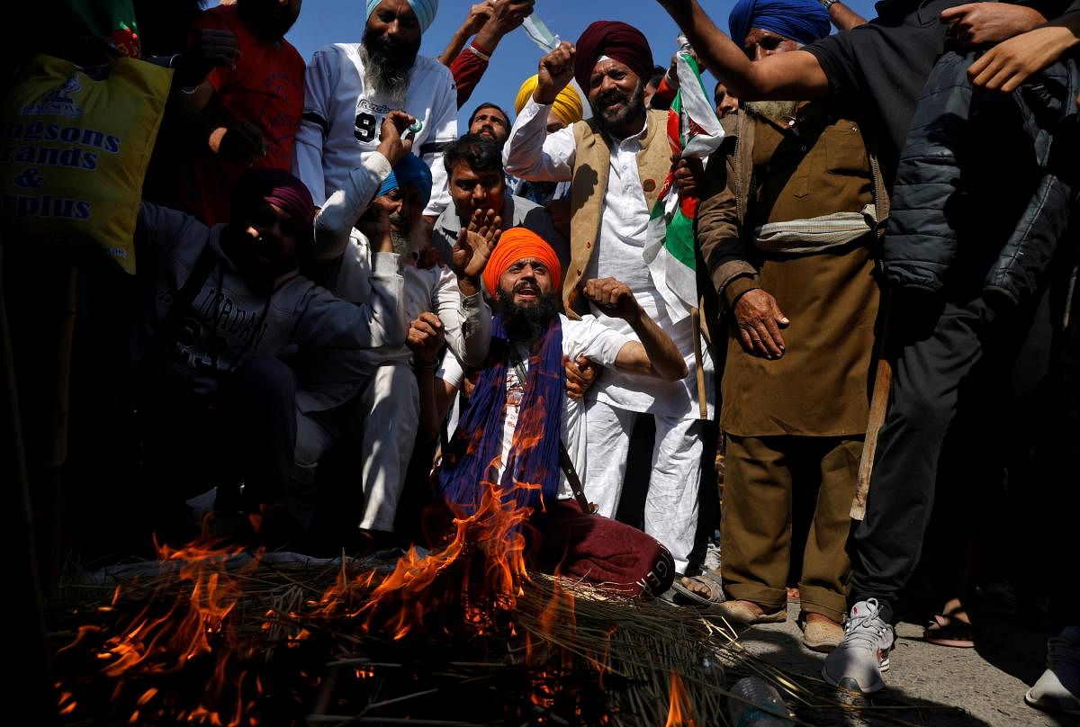Farmers shout slogans after burning an effigy during a protest against the newly passed farm laws at Singhu border near Delhi. Credit: Reuters