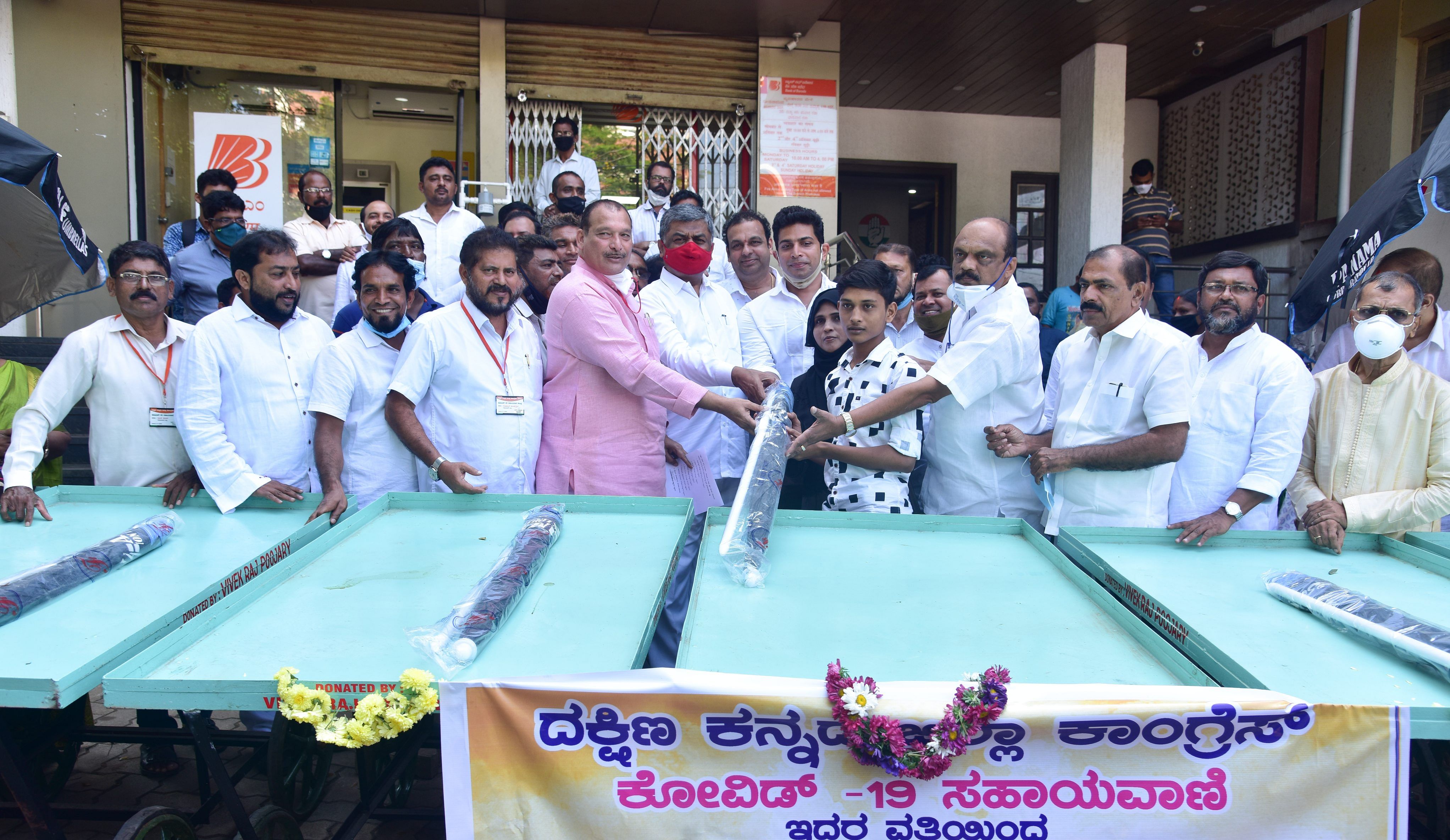 Former MLC Ivan D’Souza, MLC B K Hariprasad and others hand over a pushcart to a beneficiary in Mangaluru. The pushcarts were donated under the aegis of the Congress Covid-19 Helpline. Credit: DH Photo