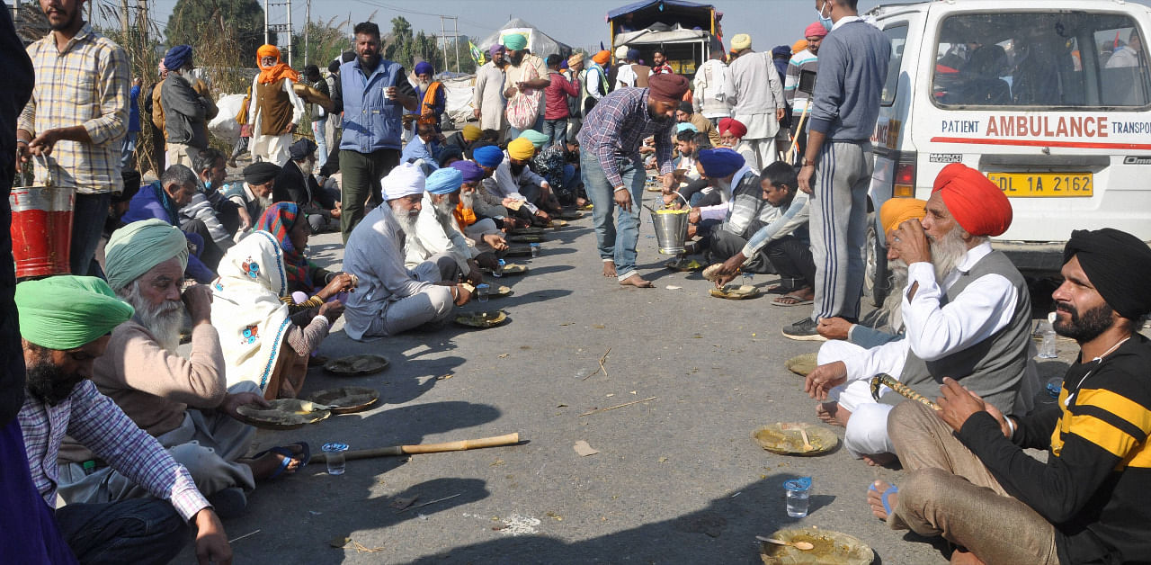 Farmers gathered at the Singhu border as part of their "Delhi Chalo" protest against Centre's new farm laws, have lunch during their agitation. Credit: PTI Photo