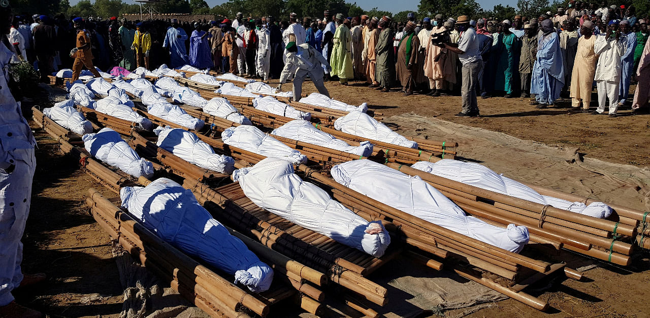Men gather near dead bodies of people who were killed by militant attack, during a mass burial at Zabarmari, in the Jere local government area of Borno state. Credit: Reuters Photo