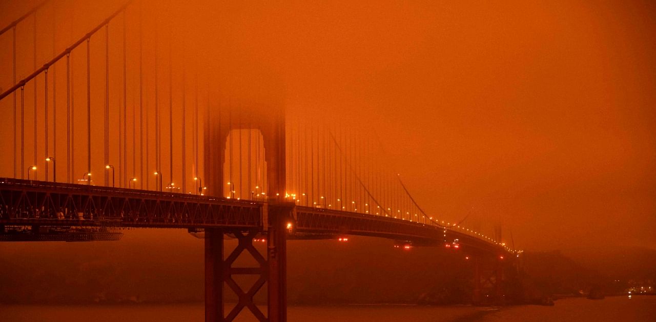 Cars drive along the Golden Gate Bridge under an orange smoke filled sky at midday in San Francisco, California on September 9, 2020. Credit: AFP Photo