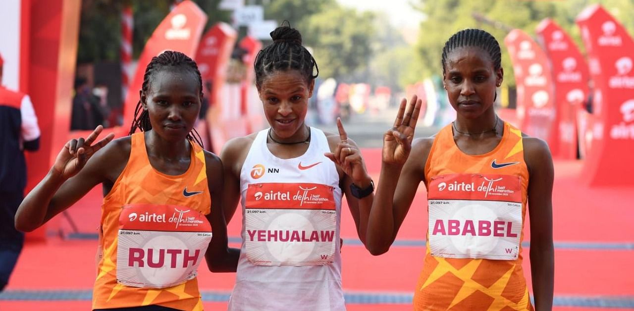First placed Ethiopian Amedework Walelegn (C) poses for a picture with second placed Kenyan Ruth Chepngetich (L) and third placed Ethiopian Ababel Yeshaneh at the finish line during the women's 2020 Airtel Delhi half marathon in New Delhi. Credit: AFP.