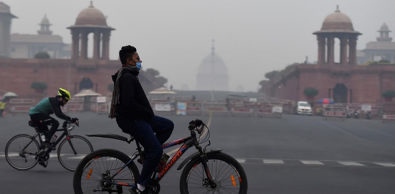 Cyclists ride through fog on a cold morning, at Vijay Chowk in New Delhi. Credit: PTI.