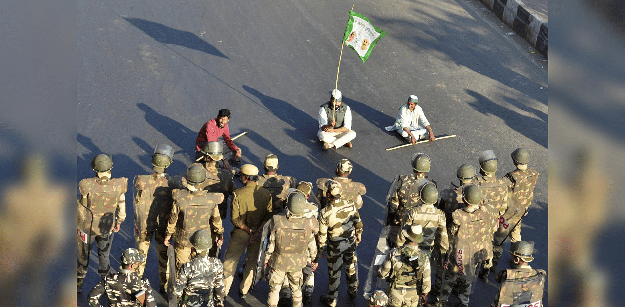 Bharatiya Kisan Union (BKU) members sit on a road, as protestors attempt to cross a police barricade at Ghazipur border during their 'Delhi Chalo' march against the new farm laws, in New Delhi, Saturday, Nov. 28, 2020. Credit: PTI Photo