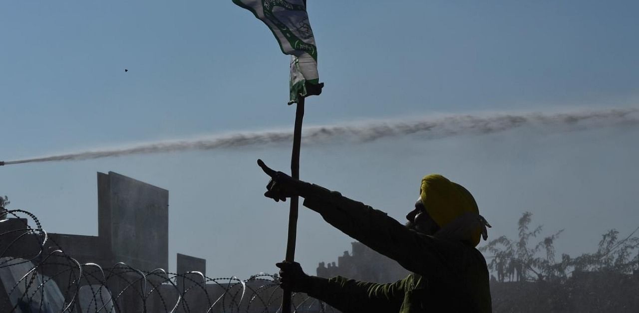 A farmer shouts slogans as police use water canon to disperse farmers. Credit: AFP Photo