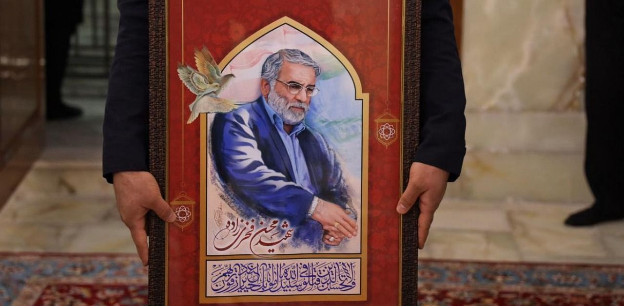 A handout picture provided by Iran's Defence Ministry on November 29, 2020 shows a servant of the Imam Reza Shrine carrying a framed painting depicting Iran's assassinated top nuclear scientist Mohsen Fakhrizadeh during his funeral procession in the northeastern city of Mashhad. Creidt: AFP/Iranian Defence Ministry/Handout.