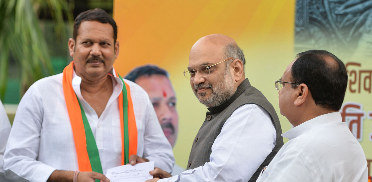 Home Minister Amit Shah gives party membership slip to senior NCP leader Udayanraje Bhosale, after the latter joined BJP, in the presence of party Working President JP Nadda, in New Delhi. Credit: PTI Photo
