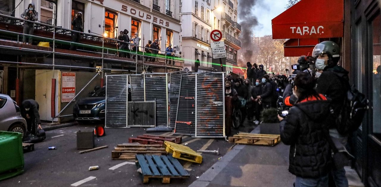 People use street barriers as protective shields, during a protest against the 'global security' draft law, which Article 24 would criminalise the publication of images of on-duty police officers with the intent of harming their 'physical or psychological integrity', in Paris. Credit: AFP Photo