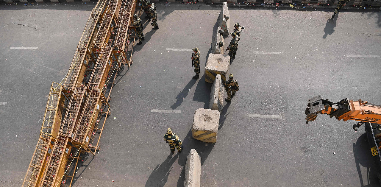Security personnel stand next to concrete and metal barriers blocking a road to stop farmers from marching to New Delhi. Credit: AFP Photo