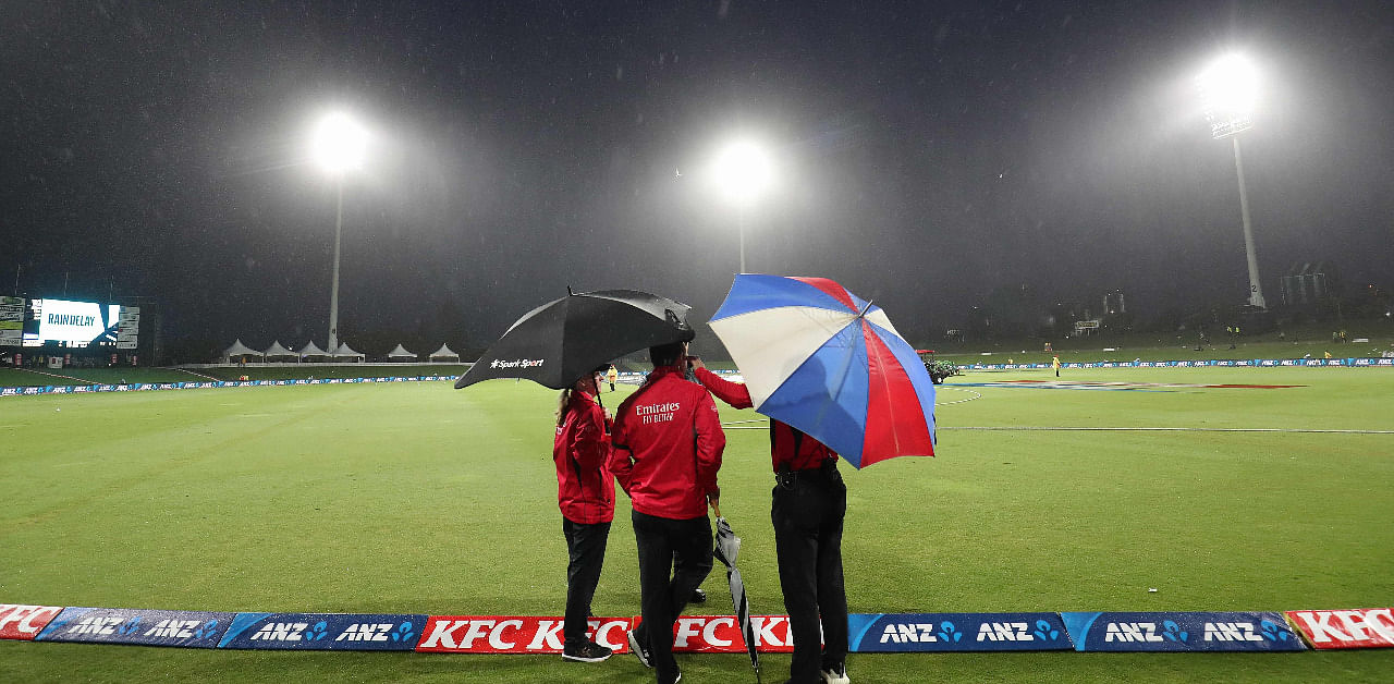 Umpires stand on the boundary as rain forces a delay in play during the third Twenty20 International cricket match between New Zealand and the West Indies at the Bay Oval in Mount Maunganui. Credit: AFP Photo