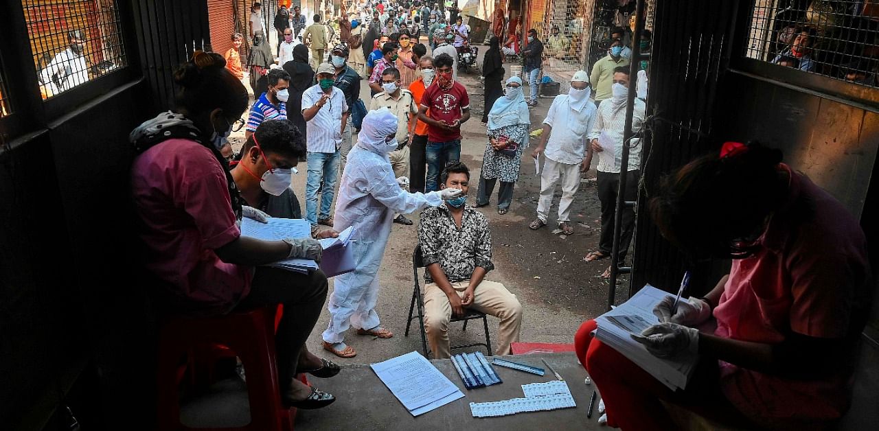 A health worker takes a nasal swab of a resident during a Covid-19 RT PCR and Rapid Antigen test, at a market in Mumbai. Credit: AFP Photo