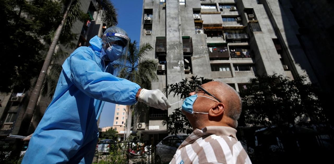 A healthcare worker wearing personal protective equipment (PPE) takes a swab from a man during a testing campaign for the coronavirus disease (COVID-19), at a residential area in Ahmedabad, India, November 27, 2020. Credit: Reuters Photo
