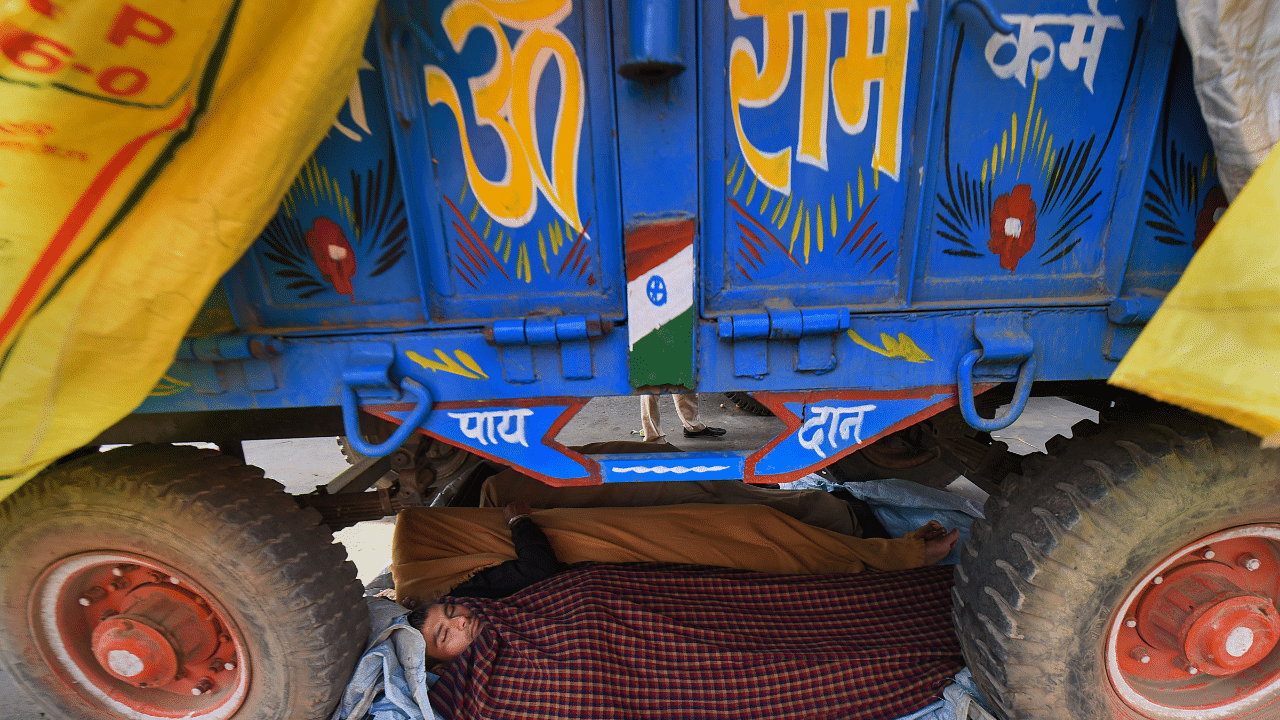 Farmers rest under a tractor trolly at the Singhu border during their 'Delhi Chalo' protest against Centre's new farm laws. Credit: PTI Photo