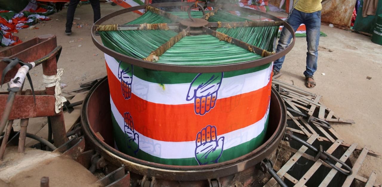 A worker pulls out a roll of cloth from a boiler after dyeing it with the symbol of India\'s main opposition Congress party at a flag manufacturing factory. Credit: Reuters Photo