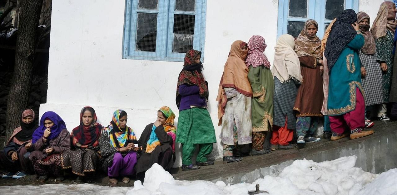 Voters wait in queues to cast their votes for the first phase of the District Development Council (DDC) elections at Rayilgund area of Gund in Ganderbal district of central Kashmir. Credit: PTI Photo
