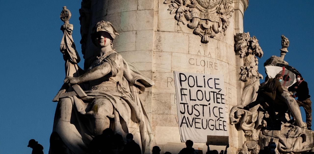 A banner reading " Police, blurring, justice blind" is seen on the statue "Le Triomphe de la Republique" (The Triumph of the Republic) in the Place de la Republique in Paris. Credit: AFP Photo