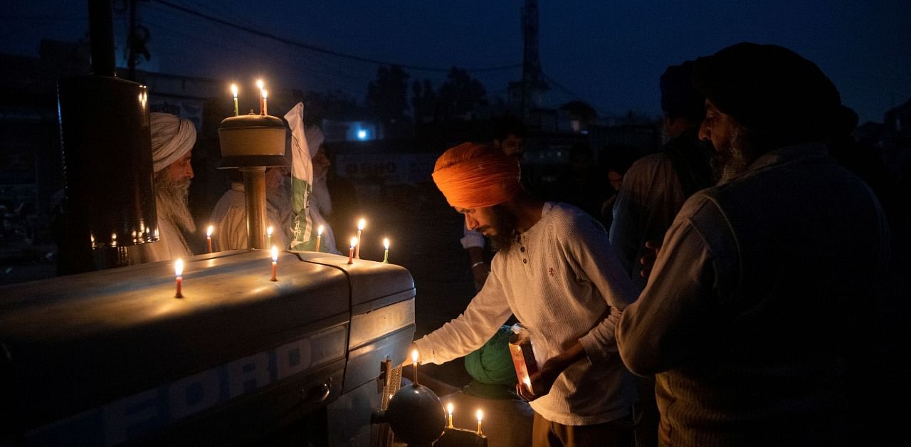 Farmers light candles to mark the 551st birth anniversary of Guru Nanak Dev, the first Sikh Guru and founder of Sikh faith, at the site of a protest against the newly passed farm bills at Singhu border near Delhi. Credit: Reuters Photo