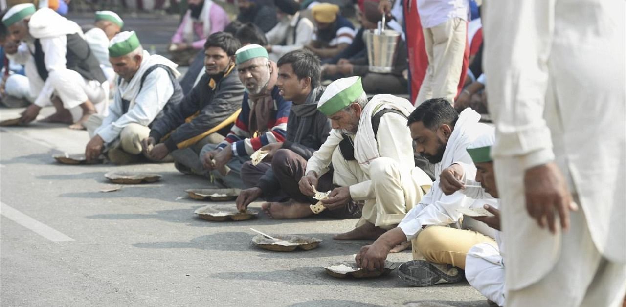 Farmers eat a meal during their 'Delhi Chalo' protest against new farm law, at Ghazipur Delhi-UP border. Credit: PTI Photo