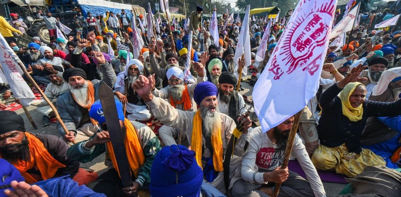 Farmers shout slogans during their ongoing 'Delhi Chalo' agitation against the new farm laws, at the Singhu border in New Delhi. Credit: PTI.