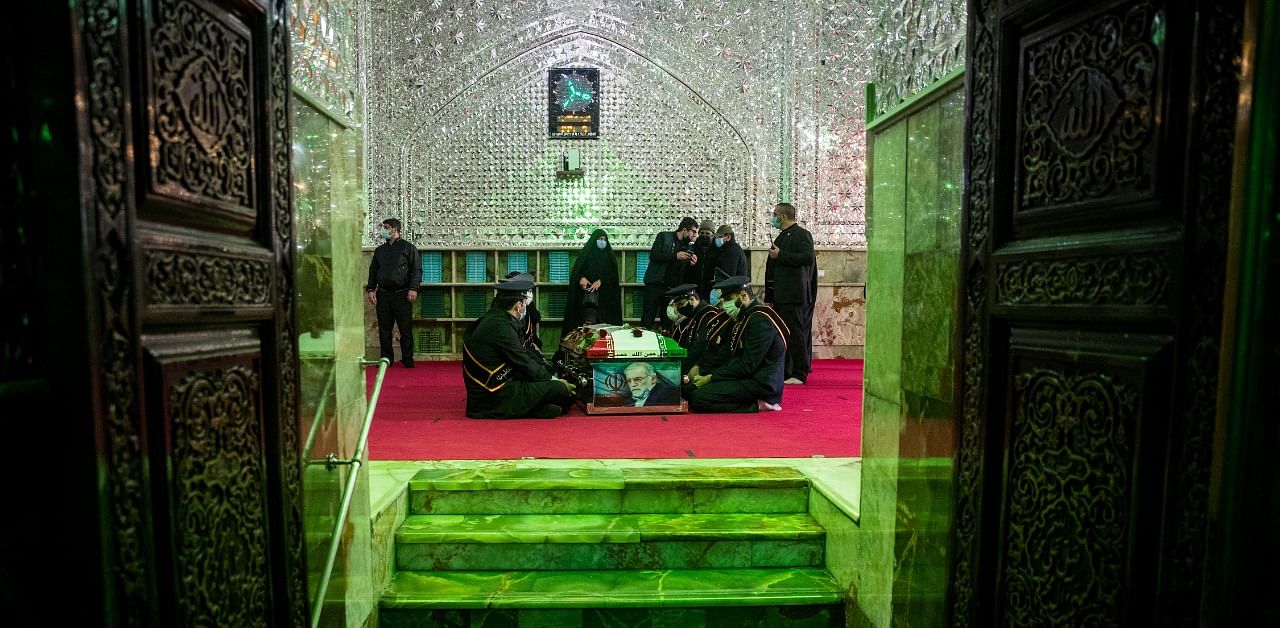 Mourners sit next to the coffin of Iranian nuclear scientist Mohsen Fakhrizadeh, during the burial ceremony at the shrine of Imamzadeh Saleh. Credit: Reuters Photo