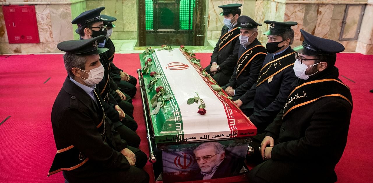 Mourners sit next to the coffin of Iranian nuclear scientist Mohsen Fakhrizadeh, during the burial ceremony at the shrine of Imamzadeh Saleh. Credit: Reuters Photo