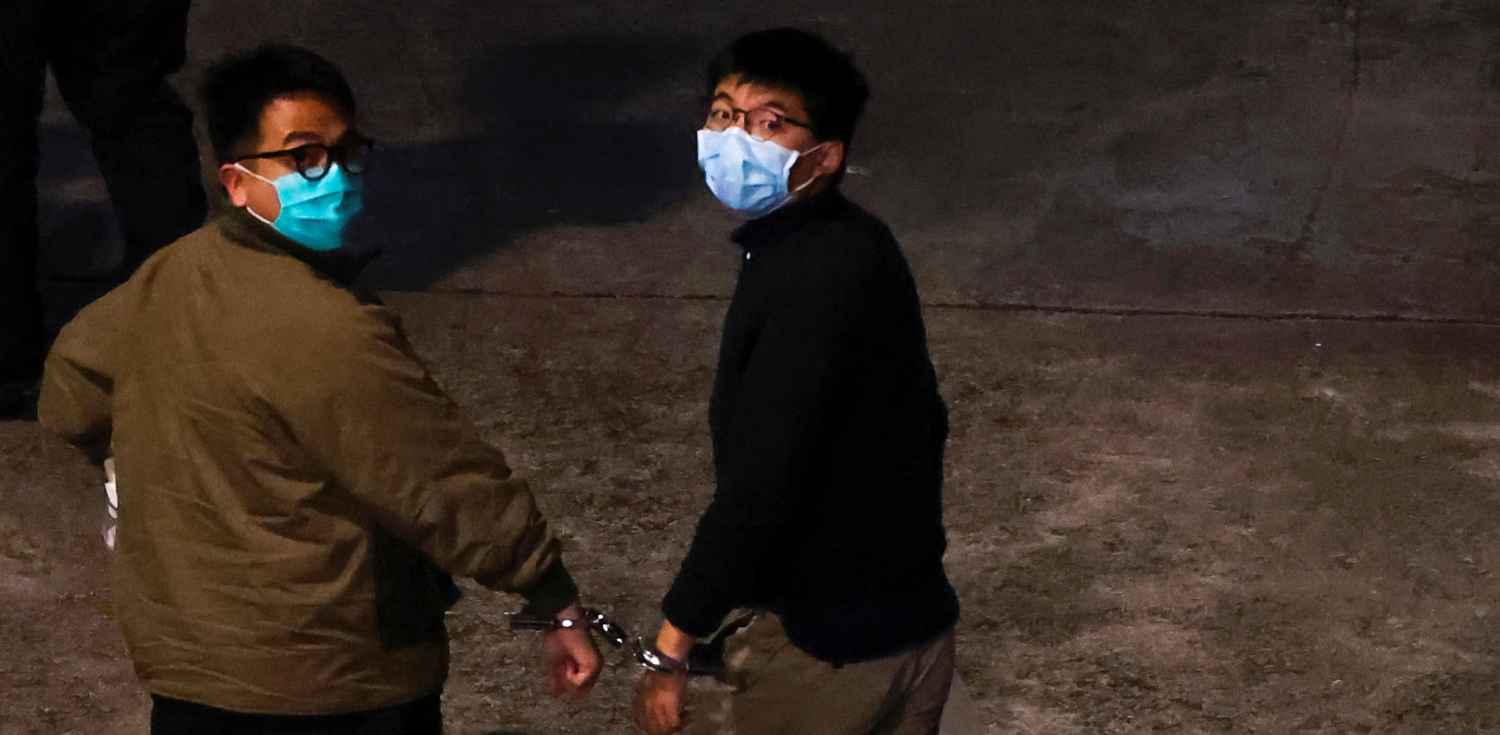 Pro-democracy activists Ivan Lam and Joshua Wong (R) arrive at Lai Chi Kok Reception Centre by prison van after being sentenced to jail for unauthorised assembly near the police headquarters during last year's anti-government protests in Hong Kong. Credit: Reuters