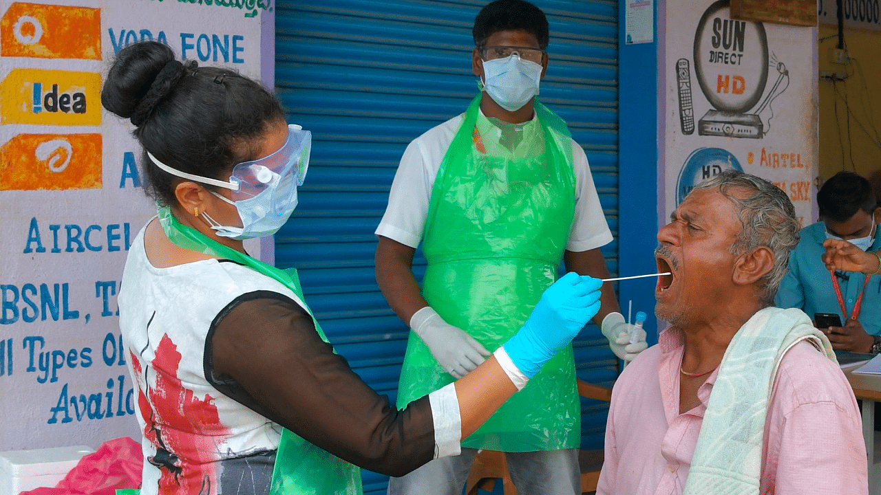 A health official collects a swab sample from a man to test for the Covid-19 coronavirus at a village on the outskirts of Bangalore. Credit: AFP Photo