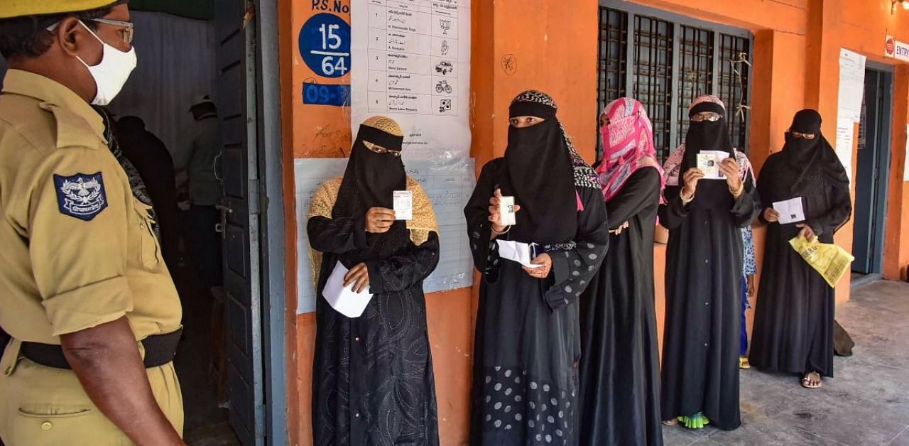 Burqa-clad women wait to cast their votes at a poling booth during GHMC elections, in old city of Hyderabad. Credit: PTI.