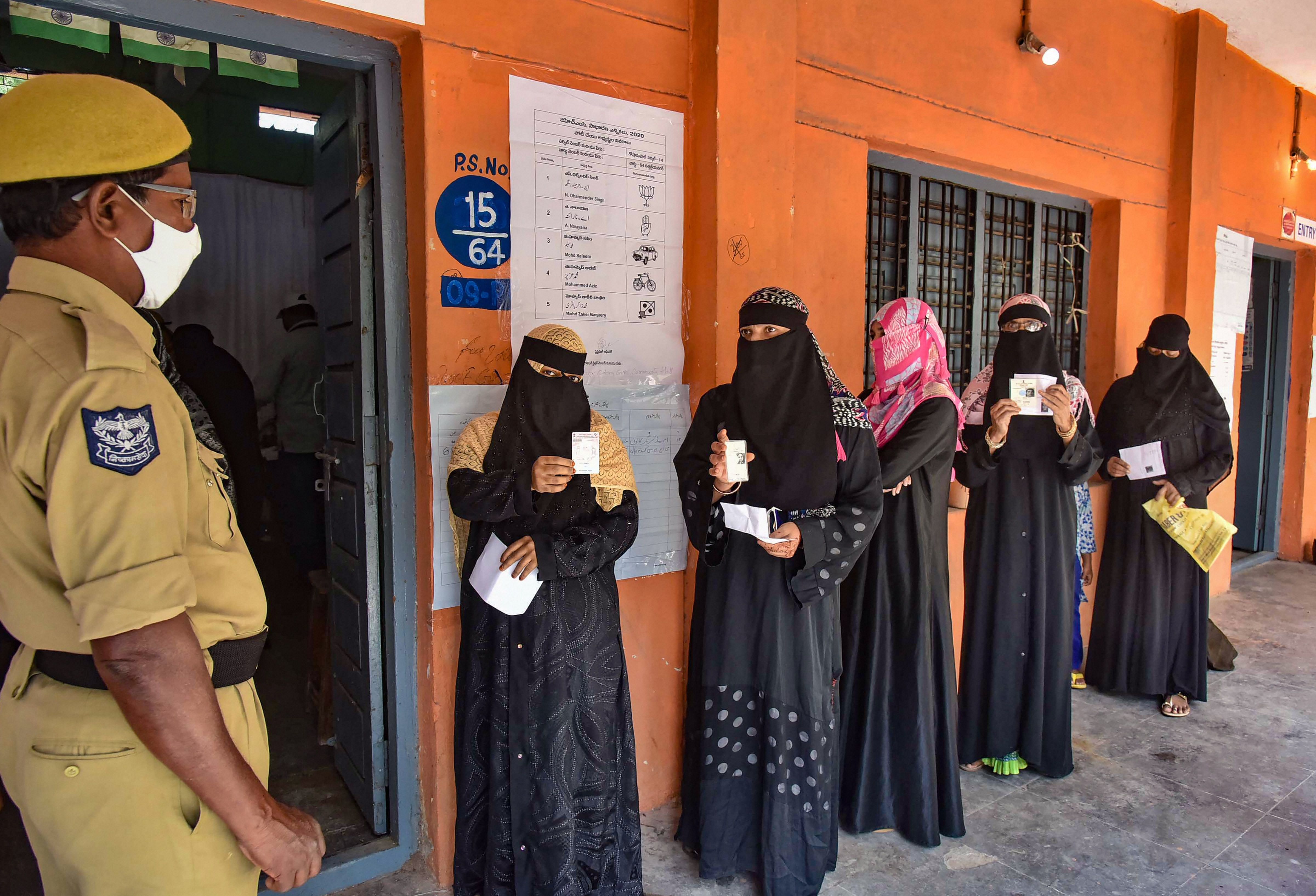 Burqa-clad women wait to cast their votes at a poling booth during GHMC elections. Credit: PTI Photo