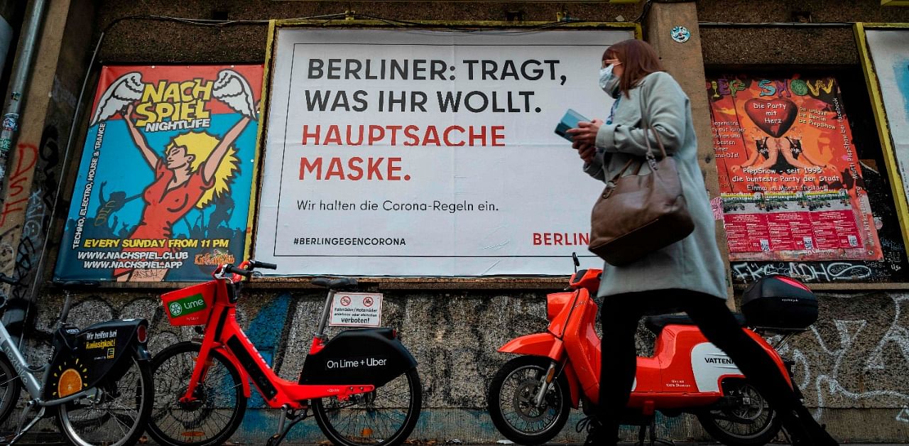 A woman wearing a face mask walks past an advertising billboard reading: "Berliners, wear whatever you want, as long as you wear a mask" amid the coronavirus pandemic. Credit: AFP Photo