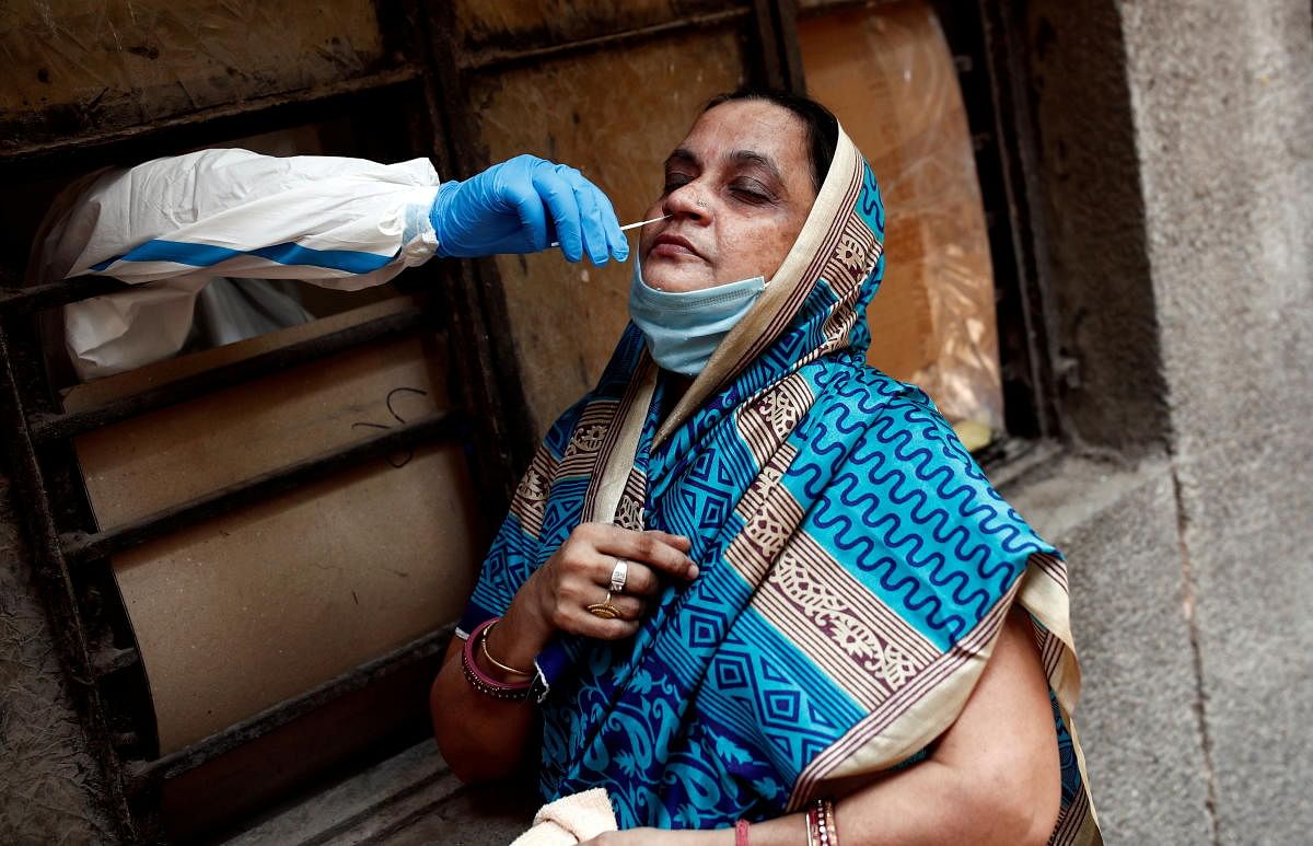 A medical worker collects a sample from a woman at a school which was turned into a centre to conduct tests for Covid-19 in Delhi. Credit: Reuters photo. 