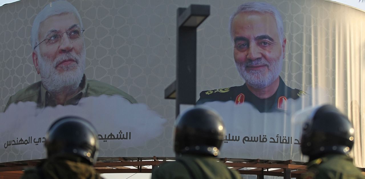 Members of the Iraqi riot police stand near a poster of Iranian commander Qasem Soleimani and top Iraqi commander Abu Mahdi al-Muhandis (L), who were killed in a US drone strike in Baghdad. Credit: AFP Photo