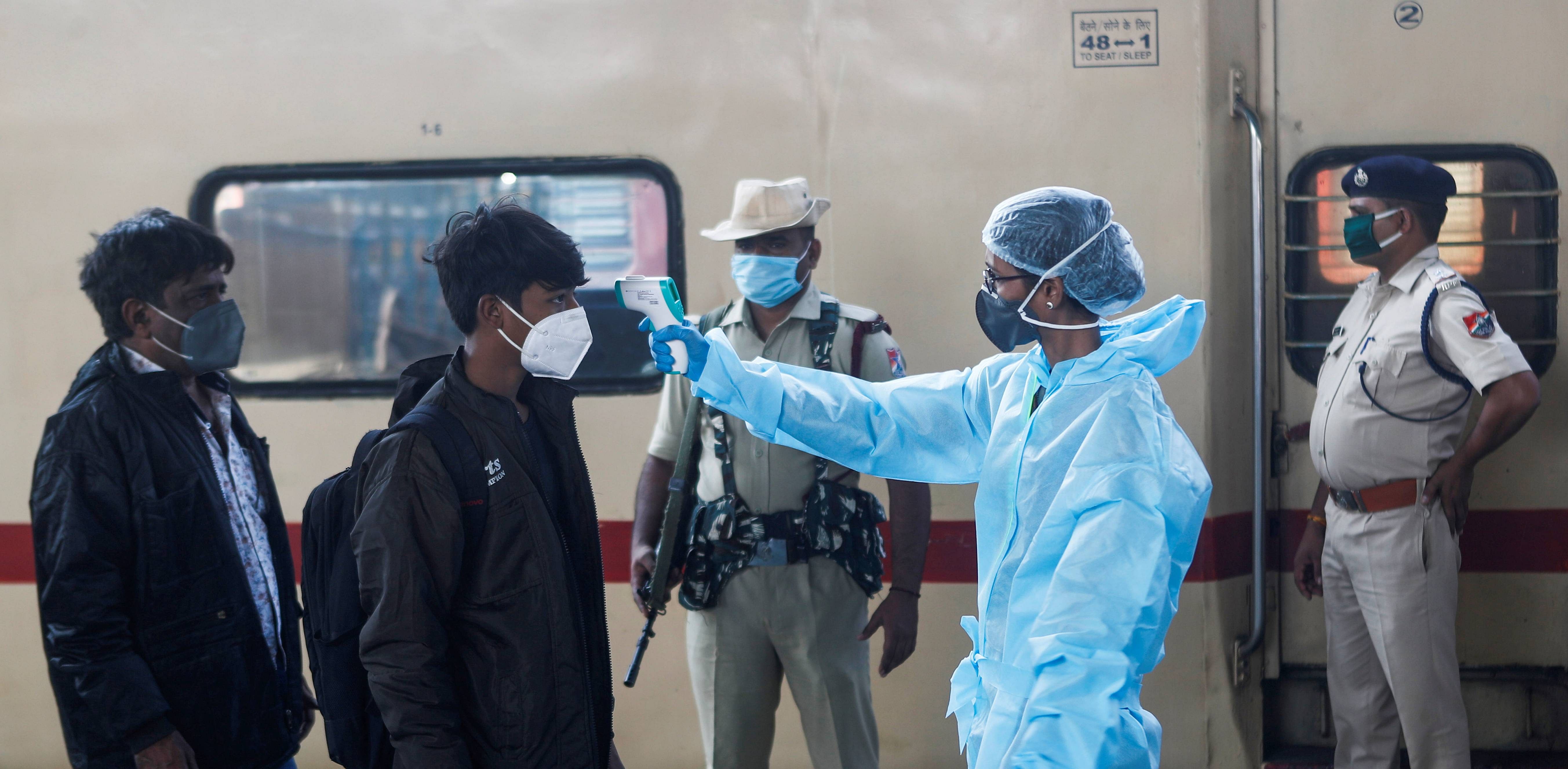 A health worker in personal protective equipment (PPE) checks the temperature of passengers at a railway station, amid the spread of the coronavirus disease (COVID-19), in Mumbai. Credit: Reuters