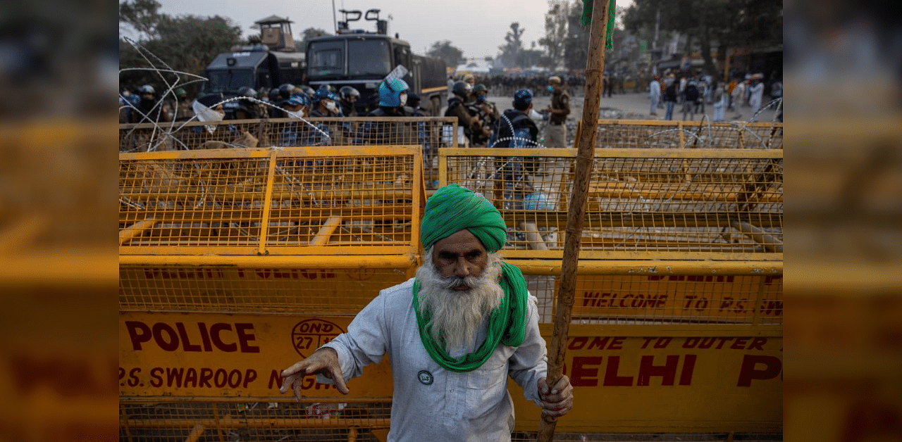 A farmer stands in front of police barricades during a protest against the newly passed farm bills at Singhu border near Delhi, India, December 3, 2020. Credit: Reuters Photo