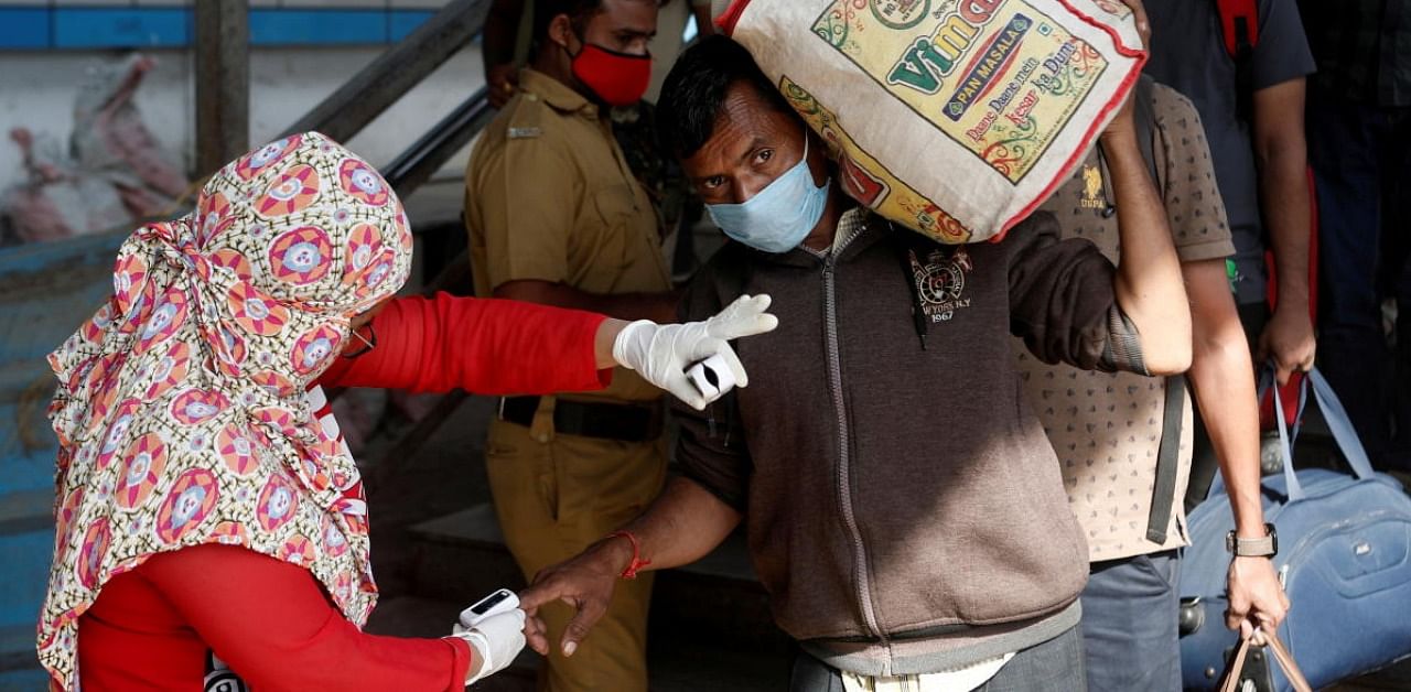 A health worker checks the pulse of a man at a railway station amidst the spread of Covid-19 in Mumbai. Credit: Reuters.
