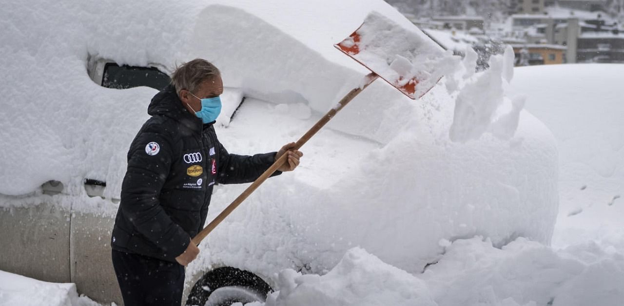 A member of Frensch ski team removes snow from a car with a shovel , in St. Moritz, Switzerland. Credit: AP/PTI.
