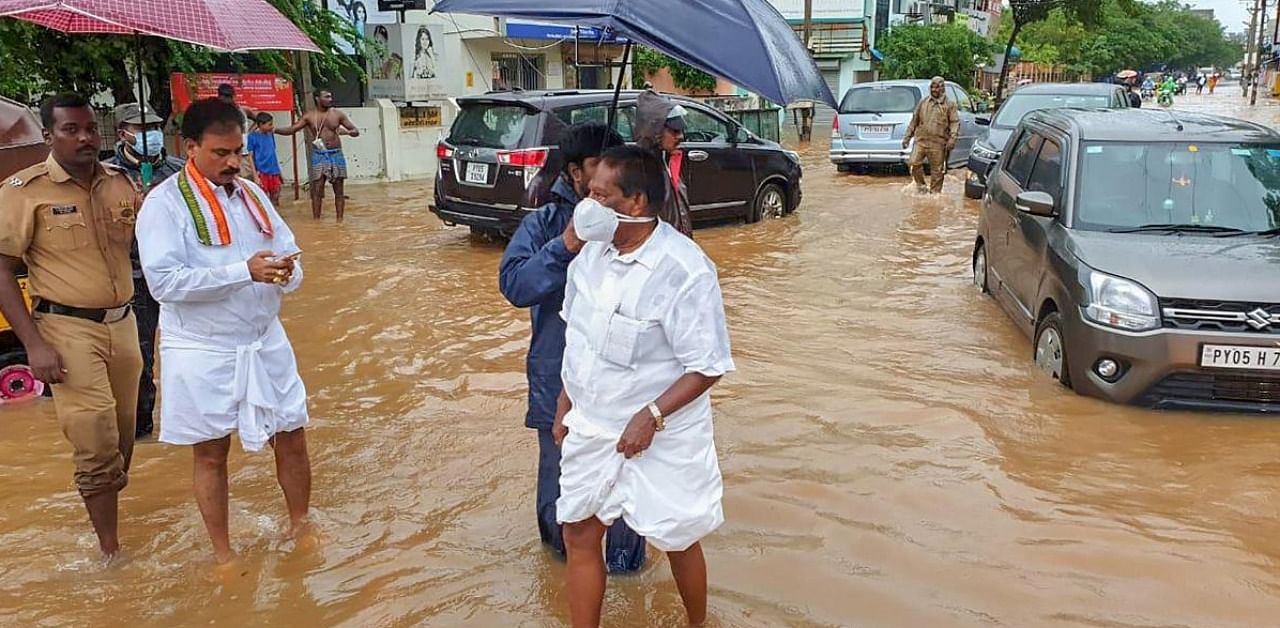 Puducherry Chief Minister V Narayanasamy wades through a flooded street to supervise the steps taken by the municipality workers to pump out the water, in Puducherry. Credit: PTI.