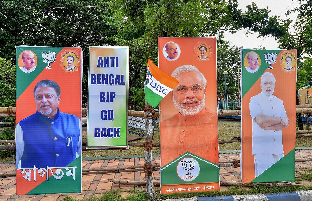 TMC activists hang a poster with the slogan "Anti-Bengal BJP Go Back" along with the posters of BJP leaders. PTI file photo