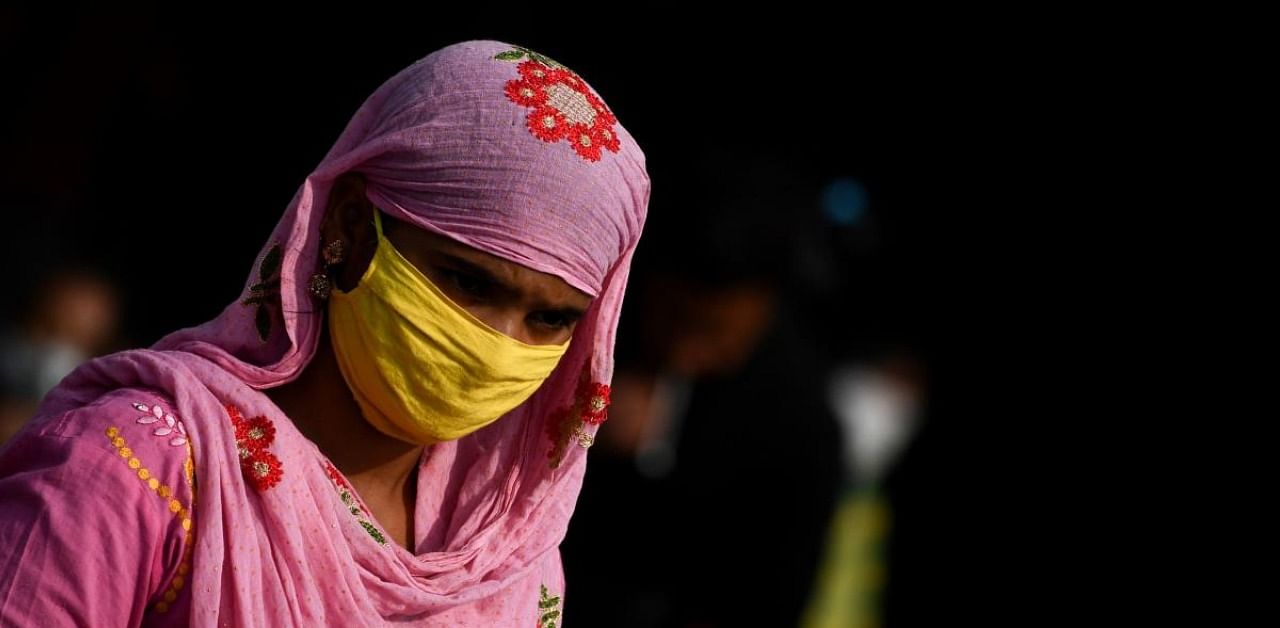 A passenger wearing a facemask as a preventive measures against the Covid-19 coronavirus waits outside a railyway station in New Delhi on December 6, 2020. Credit: AFP Photo