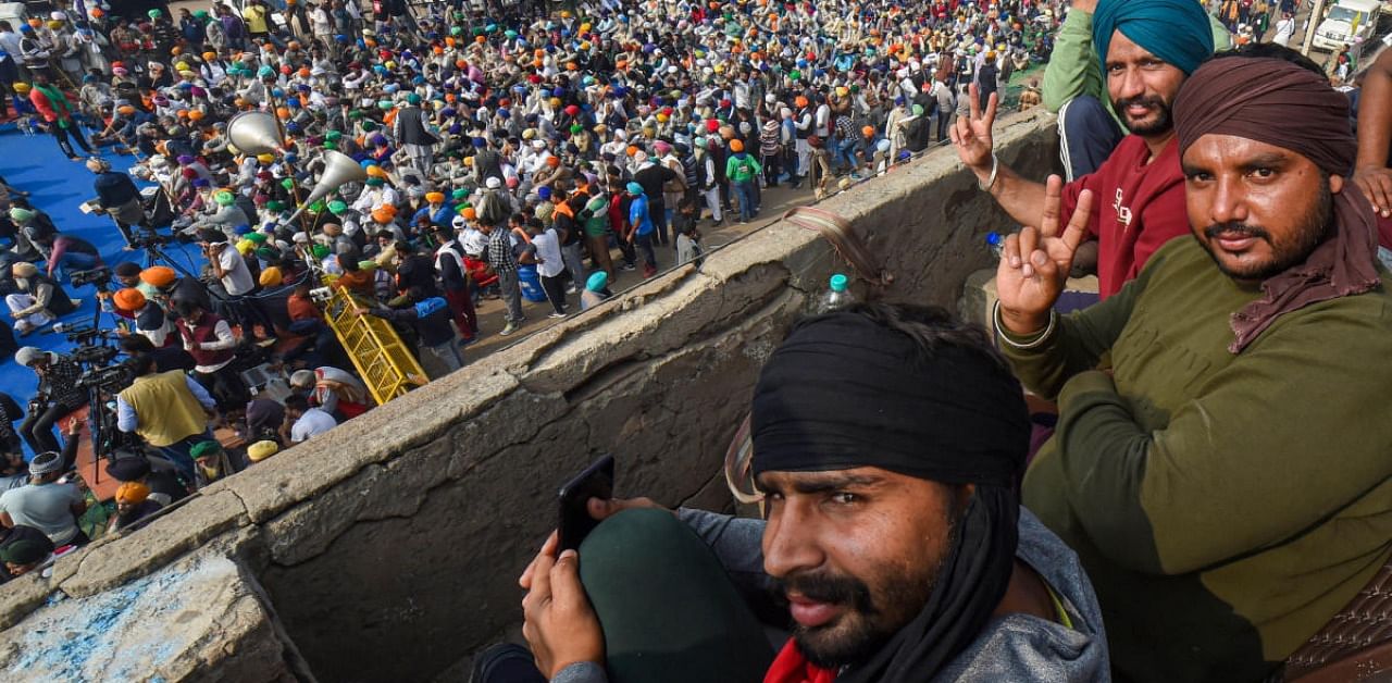 Farmers display victory sign during their agitation against the Center's new farm laws, at Singhu border in New Delhi. Credit: PTI Photo