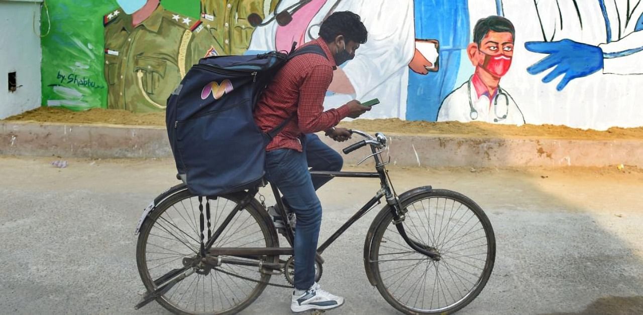 A cyclist rides past a mural, honouring the warriors of Covid-19, in New Delhi. Credit: PTI Photo