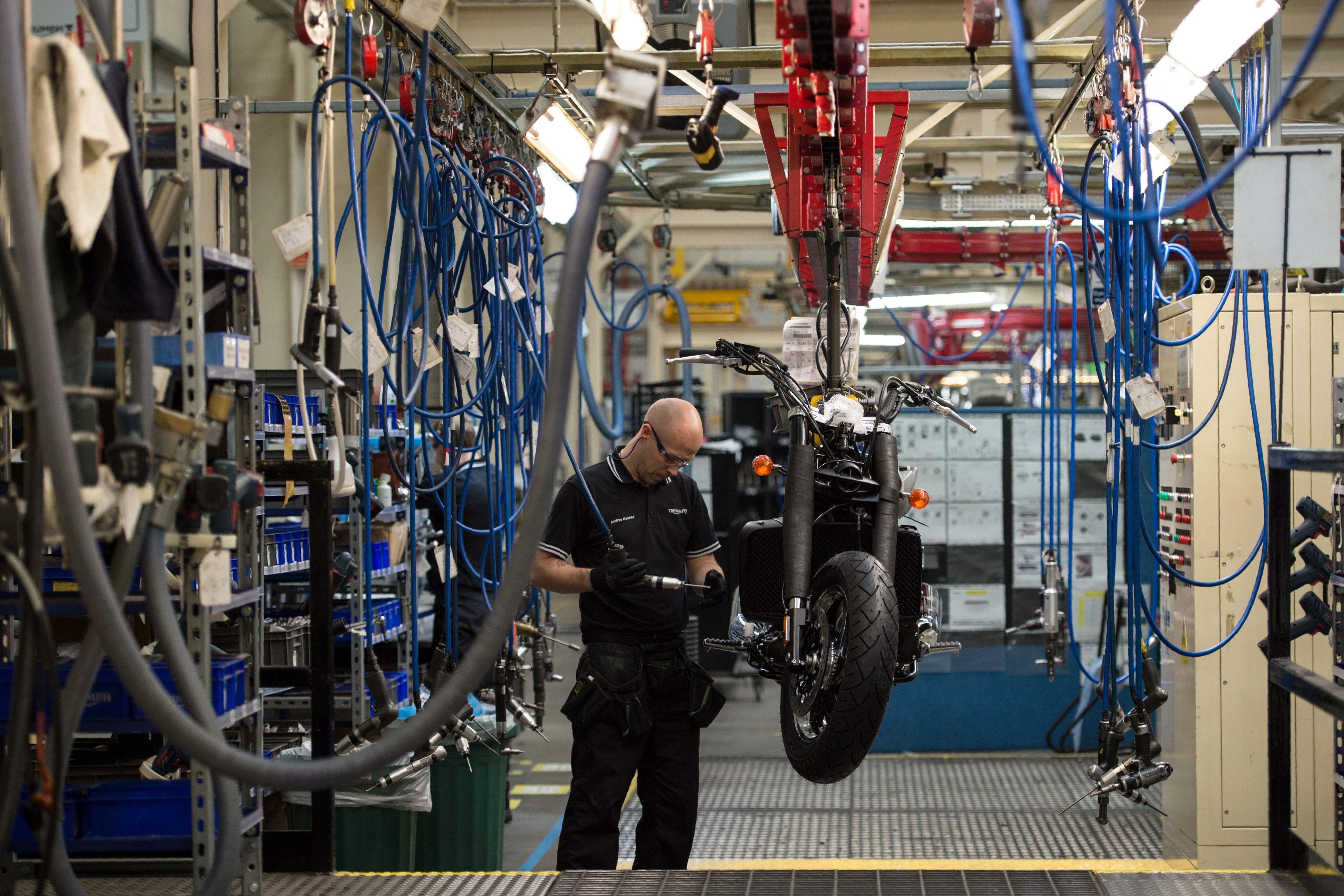 Employees assemble motorcycles on the assembly line at the Triumph Motorcycles. Credit: AFP Photo